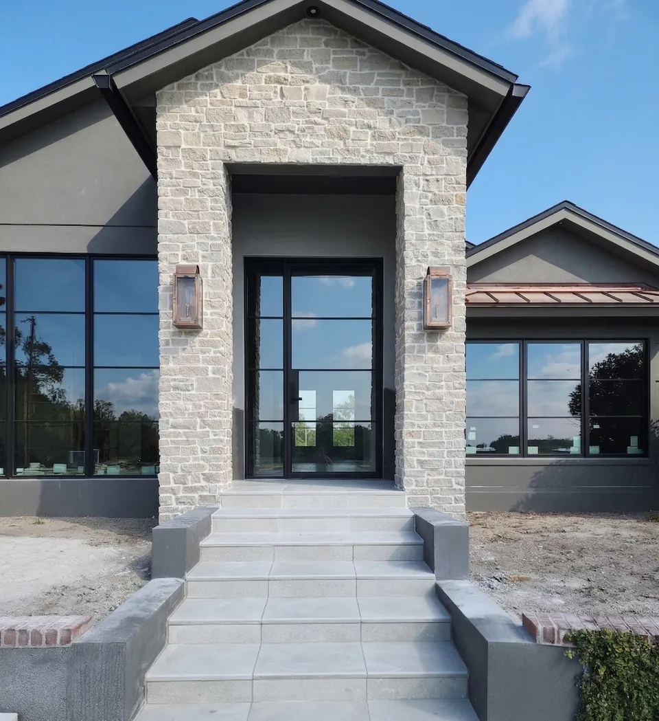 Poured concrete front entry steps finished with large-format porcelain paver treads and stucco cheek walls on a new build
