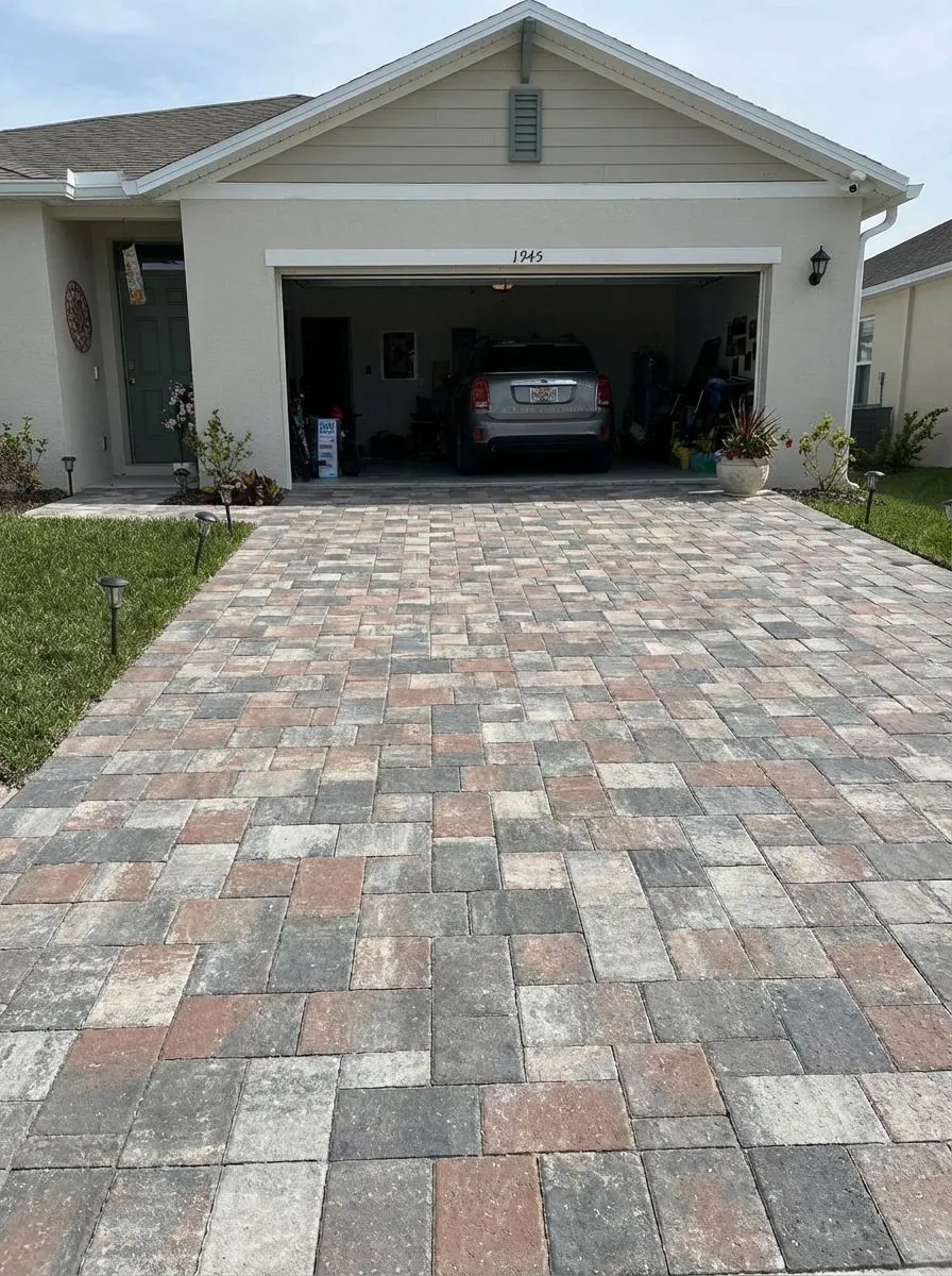 Mixed gray, tan and terracotta paver driveway in a random-ashlar pattern in front of a two-car garage
